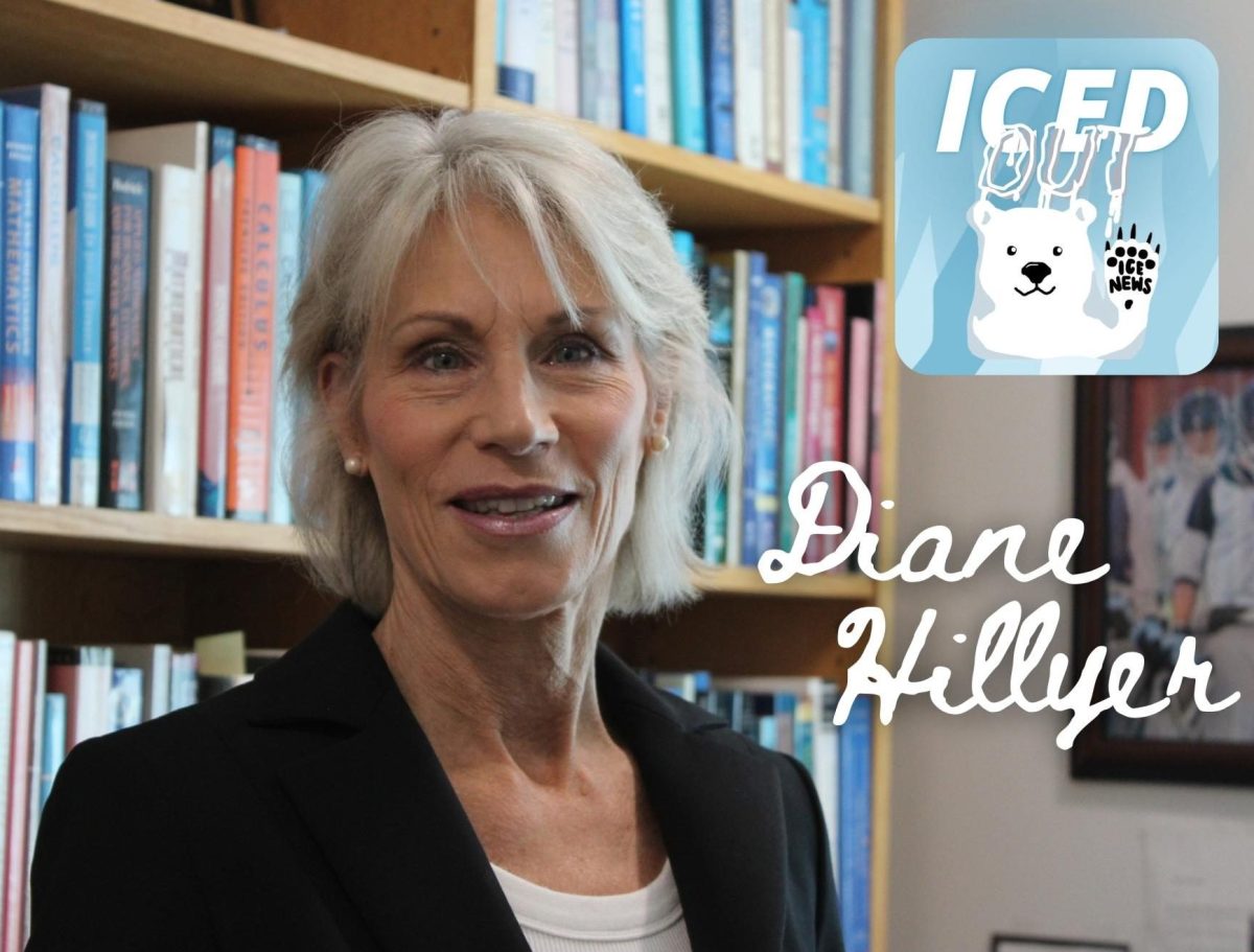 Professor Diane Hillyer stands in front of the many books gifted to her by students throughout her career that she keeps in her office.