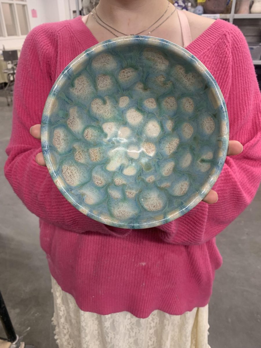 A student artist proudly shows off the design on the inside of her latest creation she plans to donate to Empty Bowls. 